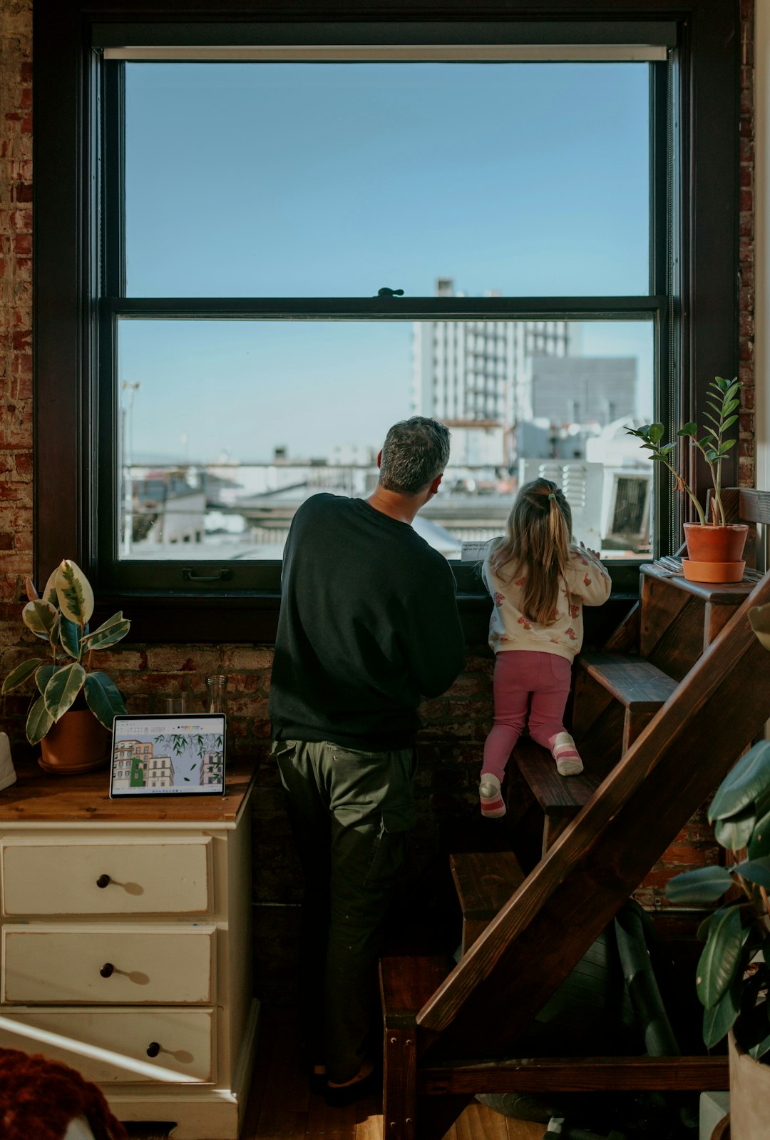 a-man-and-a-little-girl-are-looking-out-a-window-anzxhcje1v0