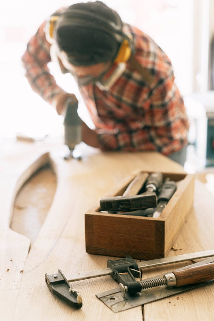 A focused woodworker using tools to craft a piece of furniture in a sunlit workshop.